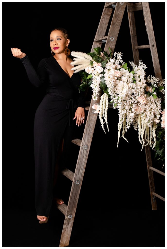 African American women posed on a wooden ladder on a black background for the 40 over 40 portrait project
