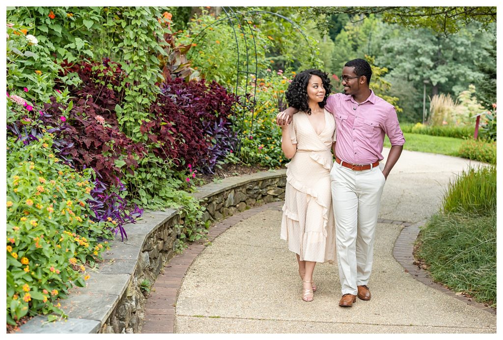 Engagement session walking shot of African American couple in a romantic outdoor garden.