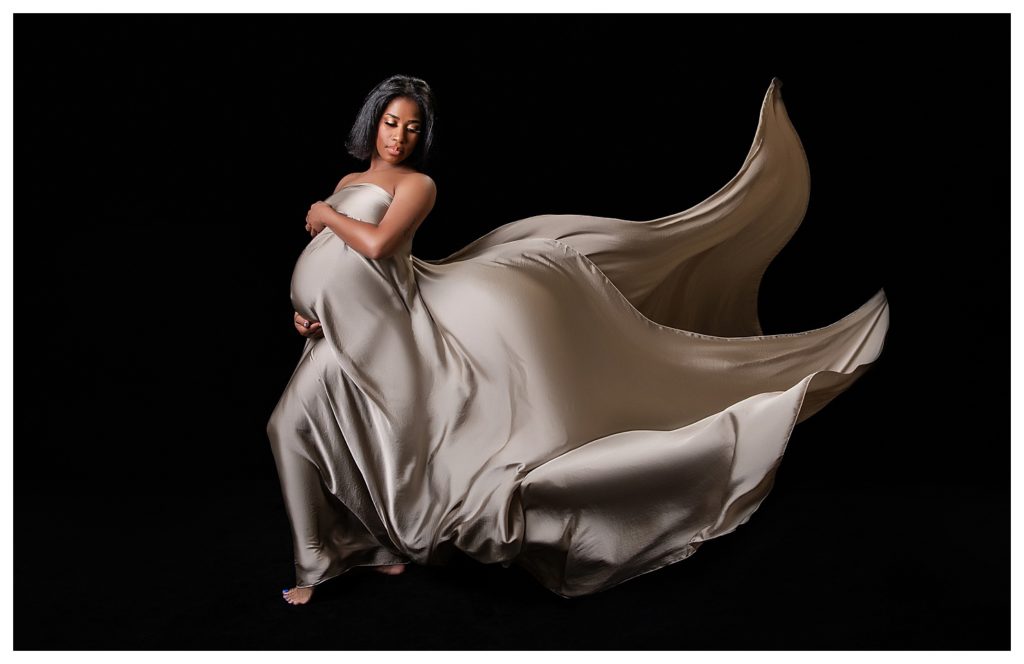 Maryland Photographer maternity studio session of an African American woman wrapped in flying fabric.