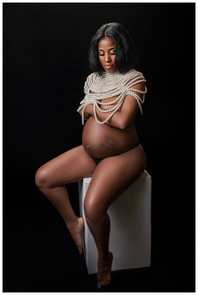 Implied nude studio maternity portrait session with mom wrapped in pearls on a black background by LaTonya Photography, a Maryland Photographer.