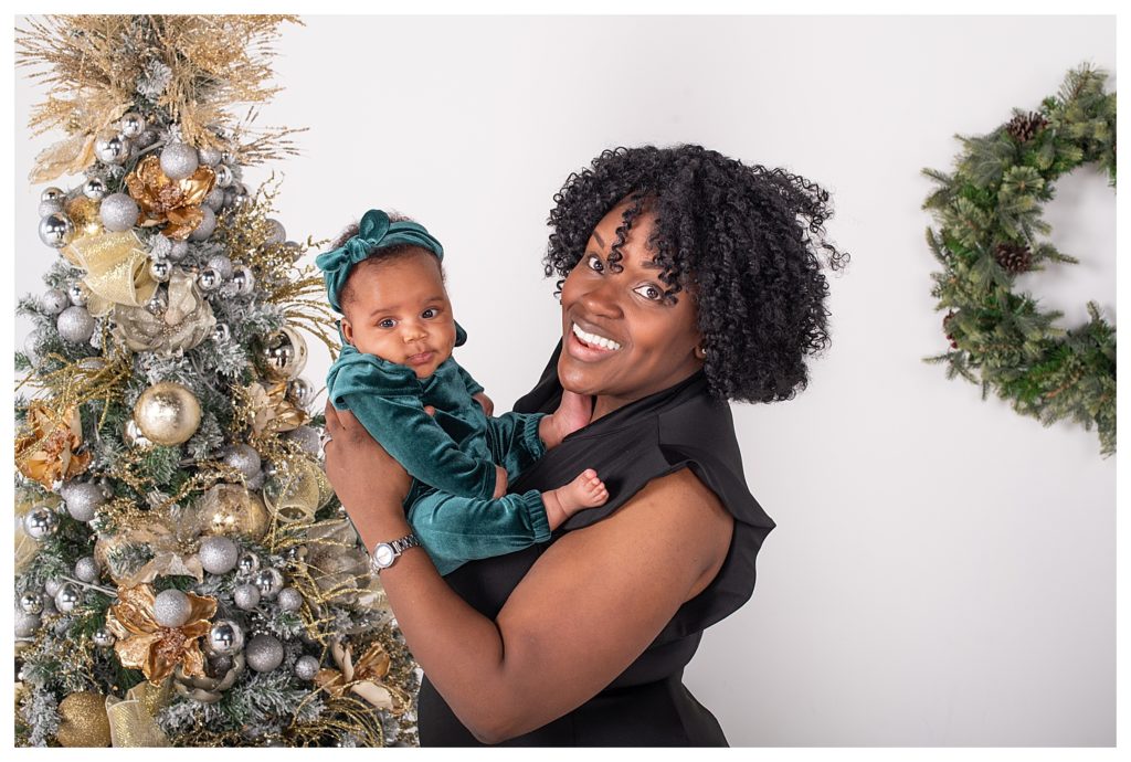 Mother and baby posed in front of a gold and silver Christmas tree during an Alexandria, VA holiday mini session.