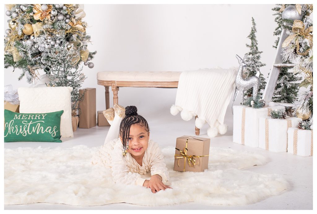 Holiday photos of little girl laying on her stomach during Christmas mini session.