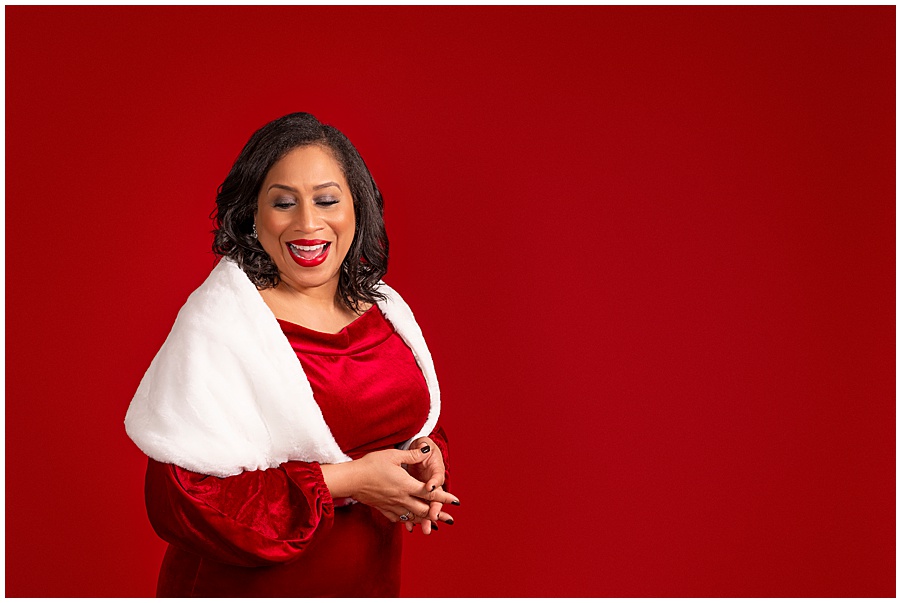 40 over 40 portrait session of African American female on a red backdrop in a red dress.