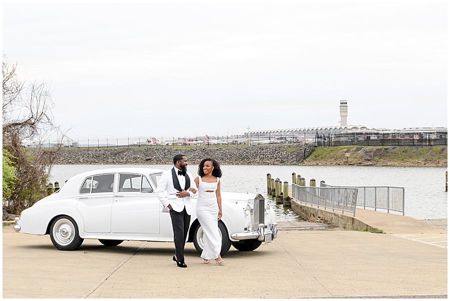 African American couple dressed in white in front of a white vintage Rolls Royce.