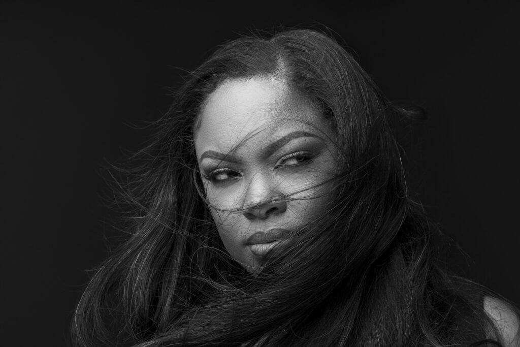 Whimsical portrait of Victoria of a face shot of her mixed gray and black hair blowing in the wind. 